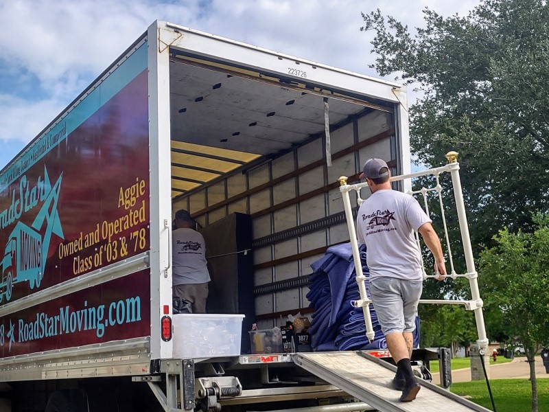 Movers carefully loading a large bed frame into a moving truck in Bryan-College Station, Tx